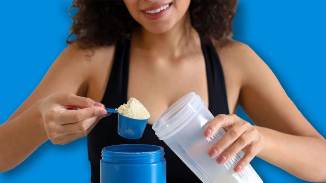 Beautiful woman making protein shake at white table indoors, closeup