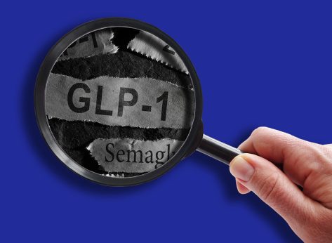 Raleigh, NC - USA - 06-13-2024: GLP-1 related drugs newspaper headlines with hand and magnifying glass