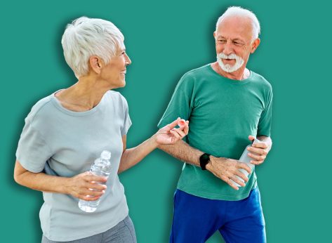 Smiling active senior couple jogging exercising and having fun and laughing together taking and walking a break in the park