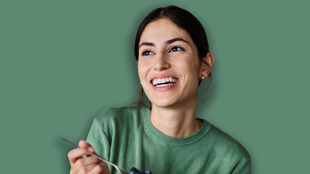 Portrait of a young woman preparing and eating breakfast, drinking juice in the kitchen at home