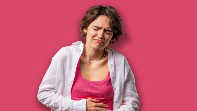 American woman squeezing belly with hands because of abdominal pain. Lady suffering from stomach ache. Healthcare, problem with menstrual period cramps or bowel flatulence concept